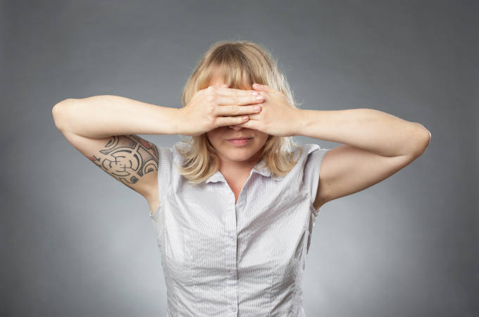 Young woman portraits on grey background, covering her eyes