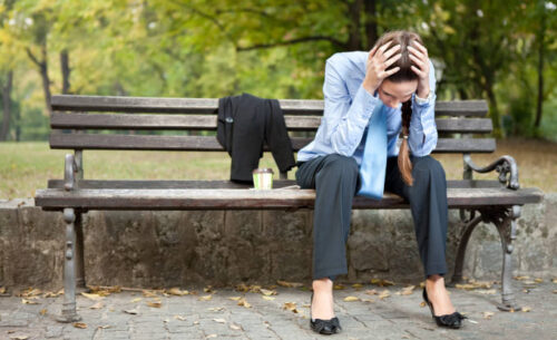 worried businesswoman sitting on bench in park